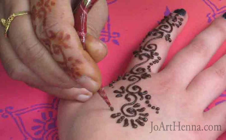 demonstration of drawing the henna design in upper palm of hand